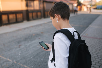 Mock up of teenage boy with wireless headphones use phone otside. Green screen