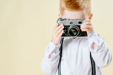 little red-haired boy with a retro camera in hands on an isolated light background