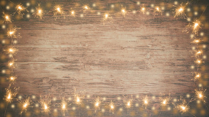frame of lights bokeh flares and sparkler isolated on rustic brown wooden texture - holiday New...
