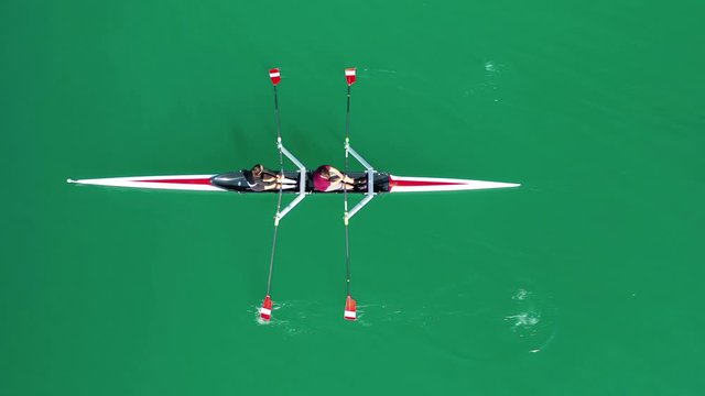 Aerial drone bird's eye view video of sport canoe operated by team of young women in deep blue sea waters