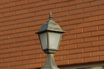 Fototapeta na wymiar one black metal lantern on a brown brick wall background