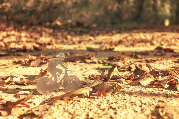Figurine de cycliste en métal sur un chemin en forêt