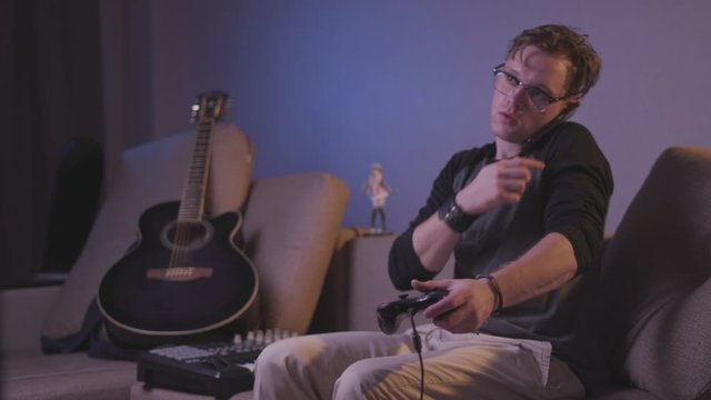 Multitasking Young Man &ndash; Gaming, Phone Call and Music at the Same Time