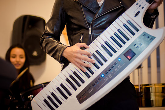 Young man playing a keytar instrument in a recording studio