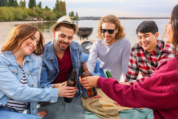 Friends drinking beer at barbecue party near river