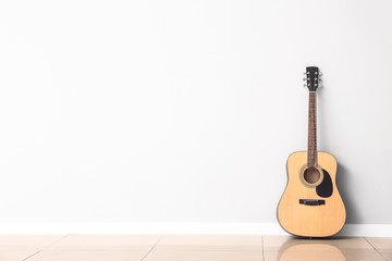 Modern acoustic guitar near white wall