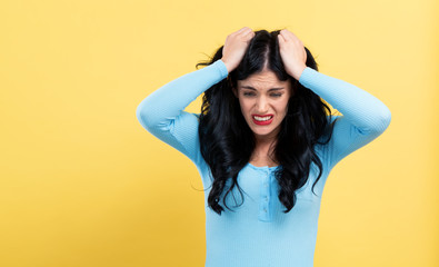 Fototapeta na wymiar Young woman feeling stressed on a yellow background