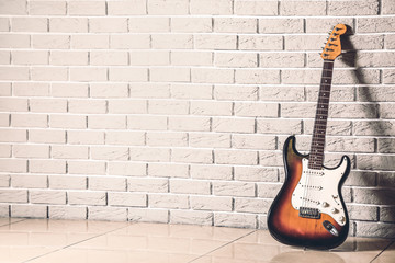 Modern bass guitar near brick wall - obrazy, fototapety, plakaty