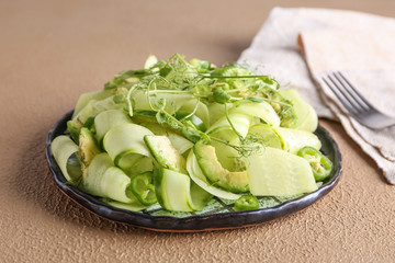 Plate with tasty cucumber salad on color background