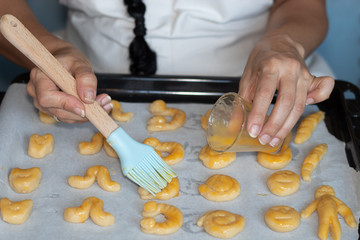 Woman's hands making marzipan, grinding almond, pouring sugar and egg, stirring everything, making individual portions, and spreading yolk
