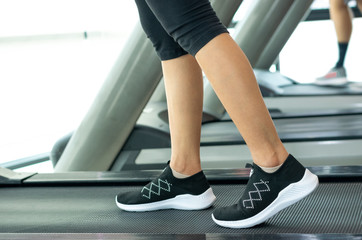 Close up foot sneakers Fitness girl running on track treadmill, Woman with muscular legs in exercise gym