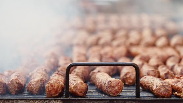 Preparing traditional romanian mici food - meat balls on grill at food festival
