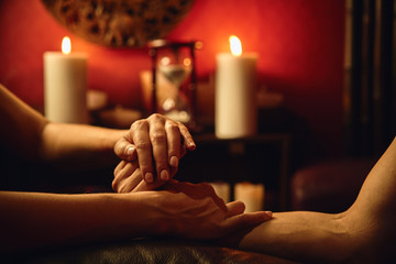 Obraz na płótnie Canvas A woman does acupressure fingers for a man. hand massage with intimate lighting. Prelude before making love. Close. Complete relaxation