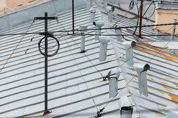Close up photo of multiple ventilation pipes from stainless steel and antenna with wires on the rooftop of living house. The ventilation system of a residential building. Inox chimney. 