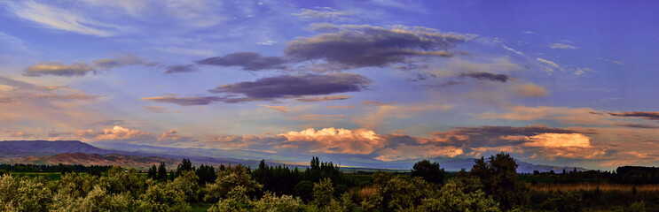 Panorama. Fairytale dawn, sunset with bright colorful clouds, on a background of rolling hills