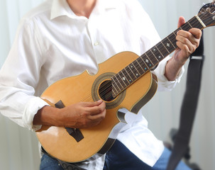 Puerto Rican man with white shirt playing a Cuatro, a national Puerto Rico musical string...
