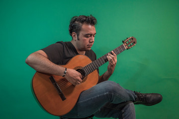 Latin guy with guitar on green background