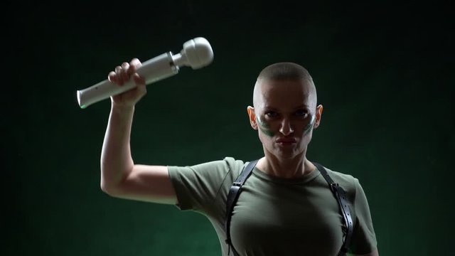 brutal bald woman with camouflage makeup holds a white massager in her hand