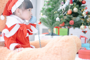 Merry christmas happy little child in santa red hat with Big teddy bear holidays in home, christmas concept