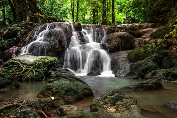 The natural background of the water flowing through rocks, natural waterfalls, blur of flowing water surrounded by various plants, the integrity of the ecosystem.