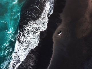 Happiness Couple enjoying on Black Sand Beach with white wave at Bali ,Indonesia