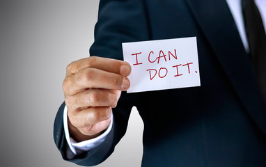 A businessman is confident in the success his holding the cards in hand that wrote the words "I can do it".