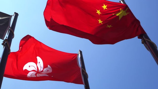 Hong Kong and Mainland China red flags in blue sky. Internal political affair conflict