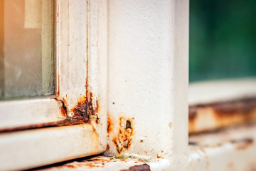 Close up of rust on an old white iron window in the corner of the frame with a blurred background