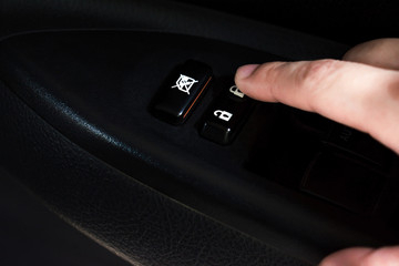 The close up of the hand is pressing the electric window button in the car.