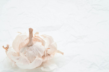 white garlic petals on a white crumpled paper background.