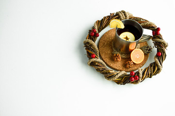 Hot flavored drink with mandarin, apple and lemon on a cork stand.