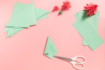 A process of making 3D fir tree from green paper on pink background. Step by step instruction, step...