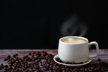 White coffee mugs on a wooden table with coffee beans on the floor.