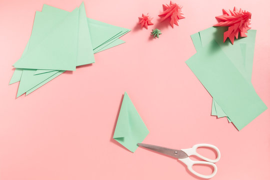A process of making 3D fir tree from green paper on pink background. Step by step instruction, step 11. Repeat step 10 from another side.