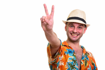 Studio shot of young happy man smiling while giving peace sign