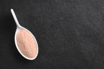 Fine pink Himalayan salt on small spoon, photographed overhead on slate with copy space on the side (Selective Focus, Focus on the salt)