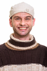 Face of young happy man smiling while wearing hat