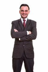 Studio shot of young happy businessman smiling with arms crossed
