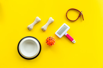 Pet's accessories like bones, collar and bowl on yellow background top view flat lay