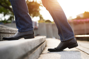 modern businessman working  close-up legs walking up the stairs in modern city. in rush hour to...