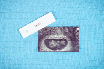 Pregnancy test and ultrasound scan of baby on background of diapers, expecting for baby
