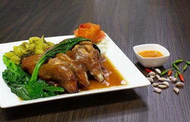 Stewed pork leg with Chinese spices in white dish on wooden background