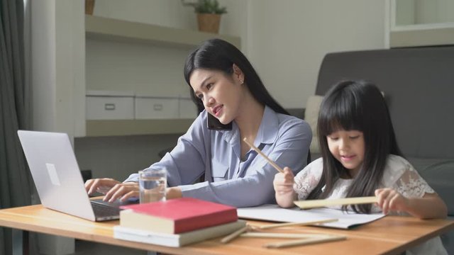 Beautiful business mom is using a laptop ann talking phone with kids at home