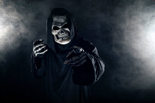 Scary looking grim reaper ghost coming out of the foggy mist.  The haunting creepy demon depicts death and evil and is a common Halloween theme as well as Day of the Dead.