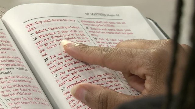 Close up shot of an African American woman reading Matthew 24 in the Holy Bible.