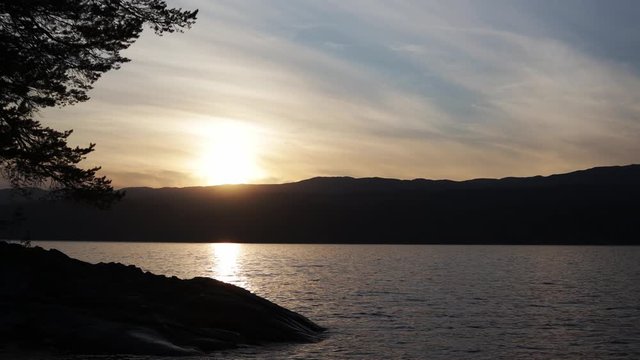 Cinematic footage. Beautiful view of the Norwegian lake at the sunset time. Evening romantic mood.