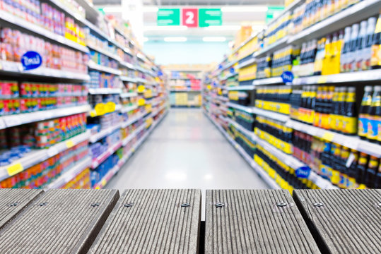 Blurred supermarket aisle with a wooden table top for design.