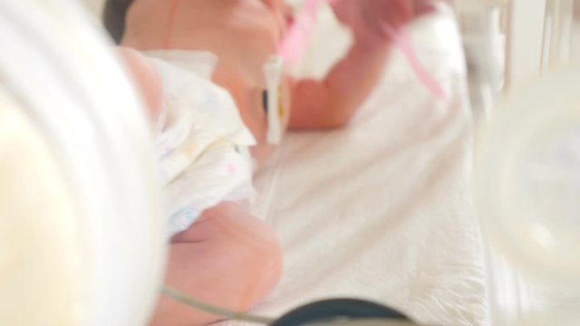Newborn in incubator, intensive hospital therapy: CCU, ICU, ITU. The tiny baby child moves his fingers, foot and leg vigorously., Closeup. Shot in 4k