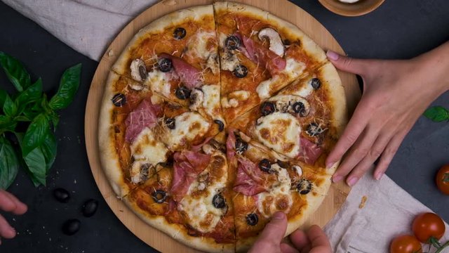 Top view of people hands taking slices of baking pizza