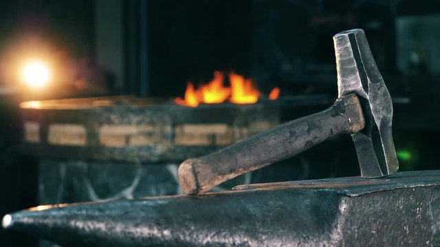 Metal hammer on anvil on a fire background.